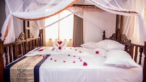 A neatly made bed with a white bedspread, a decorative headboard, and a canopy. - The Festival Hotel Suites & Spa (Mtwapa)