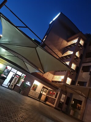 En byggnad med flera våningar och en modern arkitektonisk design, med balkonger som har räcken med dekorativa mönster och stora fönster.
