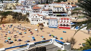 A coastal town with a beach, white buildings, and a clear blue sky.