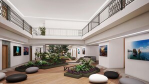 En rymlig innergård med trägolv, planteringslådor med grönska och konstverk på väggarna.