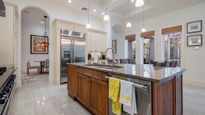 A spacious kitchen with a large island, stainless steel appliances, and pendant lighting. - Luxury Home in Naples with Private Pool & Walk to the Beach by Esthetic Stays (Naples)