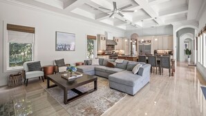 A spacious living room with a large sectional sofa, a coffee table, and a ceiling fan. - Luxury Home in Naples with Private Pool & Walk to the Beach by Esthetic Stays (Naples)