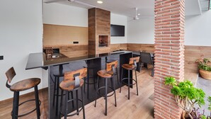 Eine moderne Küche mit Barbereich, Holzbarhocker und einer Wand in Backsteinoptik.