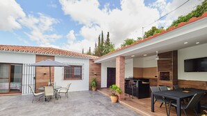 Ein moderner Patio-Bereich mit Esstisch, Stühlen und einem Grill.