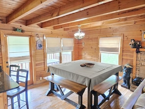 Cozy cabin-style room with a dining table, wooden bench seating area, and a fireplace.