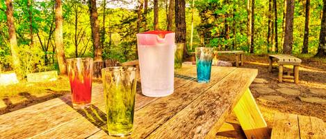 A picnic table with four glasses of different beverages.