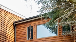 A wooden house with a patio area featuring a grill, seating, and large windows. - Outpost: Teton Shadows Granite E - Private Sauna! (Jackson)