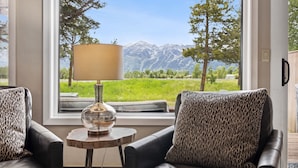 A room with a view of mountains, a table with a lamp, and two leather sofas with leopard print cushions. - Outpost: Teton Shadows Granite E - Private Sauna! (Jackson)