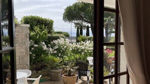 Un patio abierto con piso de piedra, plantas en macetas y mobiliario exterior.