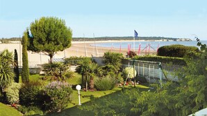 Vista costera con playa, una bandera y un área cercada con plantas.