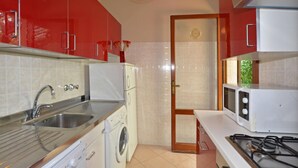 Une cuisine équipée d’un lave-linge, d’un évier, d’un four à micro-ondes et d’une cuisinière.