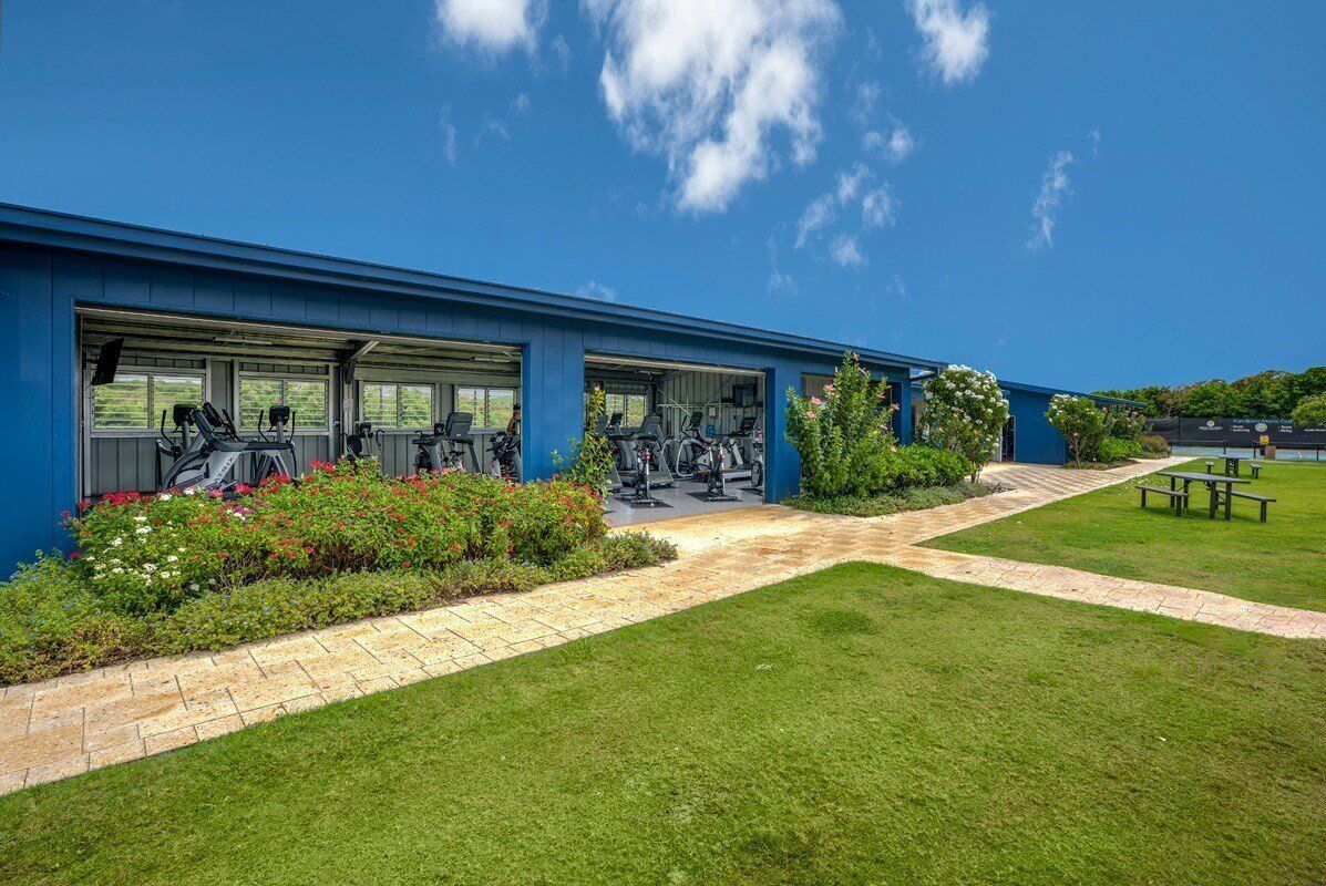 A gym with exercise equipment, a covered outdoor area, and a picnic table.