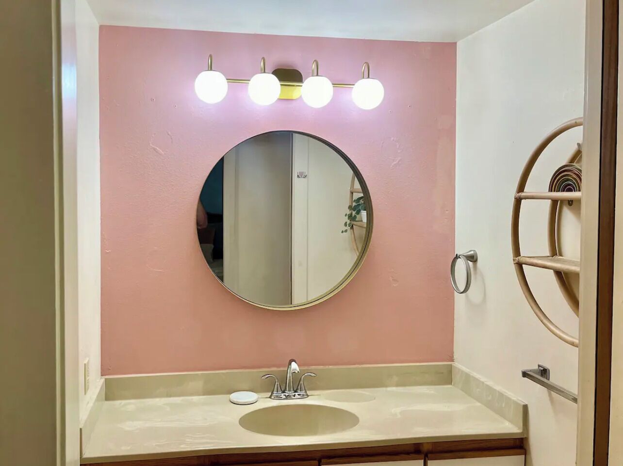 Un baño con un espejo redondo, un lavamanos y un tocador.