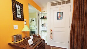 Una habitación pequeña con una mesa de madera, un tostador, una lámpara y una puerta blanca con un dibujo.