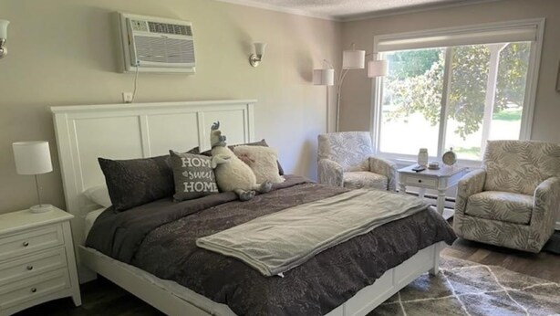 A bedroom with a bed, nightstands, a chair, and a window with a view. - Adventure Acres- Suite B8  (Holly)