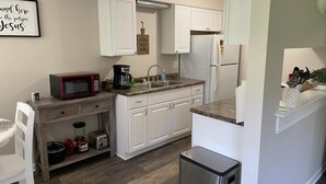 A modern kitchen with white cabinets, a stainless steel refrigerator, a microwave, and a coffee maker. - Adventure Acres- Suite B8  (Holly)