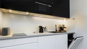 Una cocina moderna con armarios blancos, un microondas negro, una cafetera y un lavavajillas.