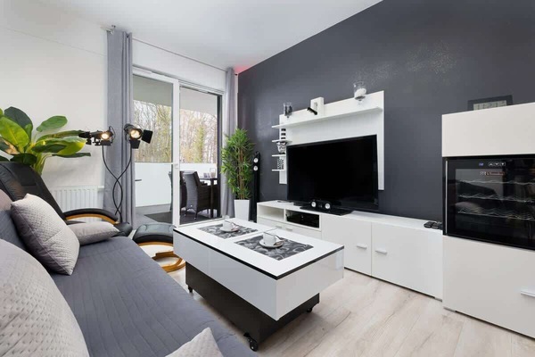 A cozy seating arrangement with a coffee table, TV, sofa, and decorative items, creating a comfortable living space. The color scheme remains neutral and contemporary.