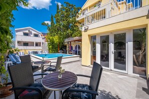 Ein Poolbereich mit Sitzgelegenheiten im Freien und Blick auf ein Gebäude mit Balkon.