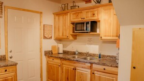 A kitchen with wooden cabinets, a microwave, a sink, and a countertop. - Aspen Ridge Cabin WIFI, 2bed+1Bath, 20mins to Yellowstone (Island Park)