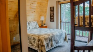 A cozy bedroom with a wooden ceiling, a bed with a plaid blanket, a nightstand with a lamp, and a motivational quote on the wall. - Aspen Ridge Cabin WIFI, 2bed+1Bath, 20mins to Yellowstone (Island Park)