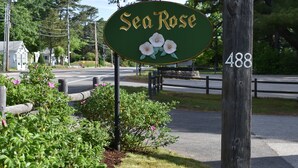 A green sign with 'Sea Rose' and a flower design, mounted on a wooden post with the number '488' beside it.