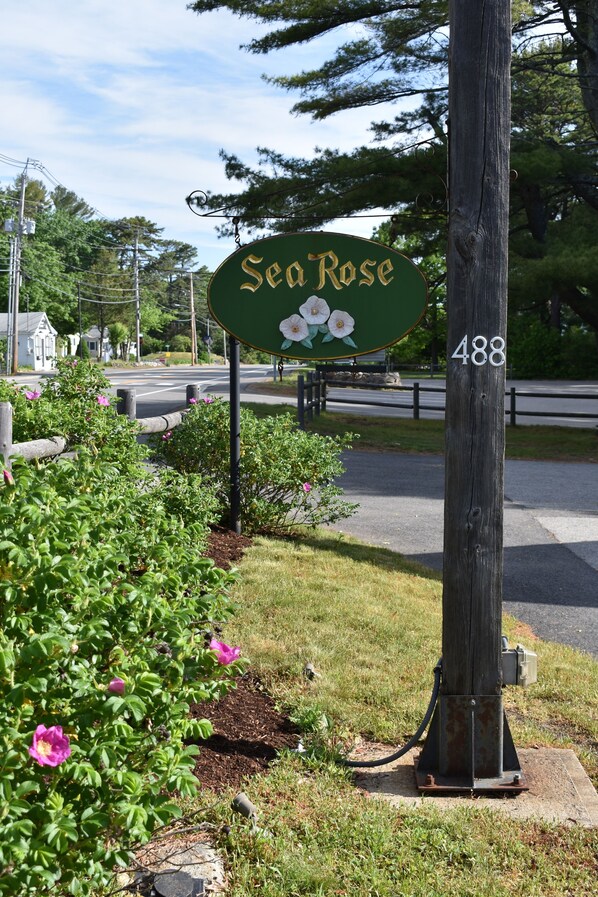 A green sign with 'Sea Rose' and a flower design, mounted on a wooden post with the number '488' beside it.