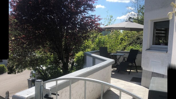 A balcony with a metal railing, a table, and a chair.