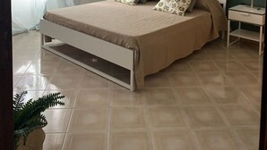 A bedroom with a bed, a nightstand, a ceiling fan, and a window with curtains. - Villa Ale - Fontane Bianche  (Fontane Bianche)