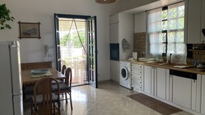 A kitchen with a washing machine, a dining table with chairs, and a large window with curtains. - Villa Ale - Fontane Bianche  (Fontane Bianche)