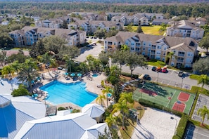 An aerial view of a residential complex with multiple apartment buildings, a swimming pool, and a basketball court. - Close to Disney Condo 3 Bed / 2 Bath In Gated Community (Kissimmee)