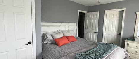Une chambre à coucher avec un lit, un ventilateur de plafond et des portes blanches.