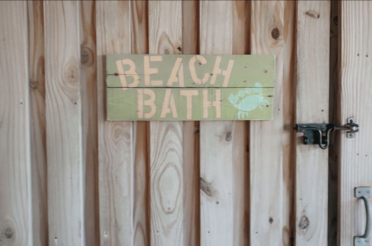 Une porte en bois avec une pancarte indiquant « DOUCHES DE PLAGE ».