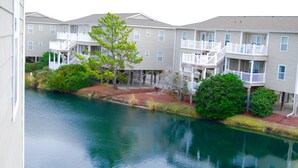 Un ensemble d’appartements situé au bord de l’eau, doté de nombreux balcons et offrant une vue sur un fleuve paisible.