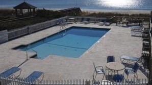 Une piscine avec des chaises longues et un kiosque, offrant une vue sur la plage.