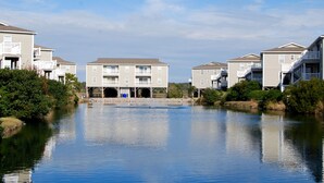 Un immeuble résidentiel situé au bord de l’eau, doté de nombreux balcons et d’une entrée centrale.