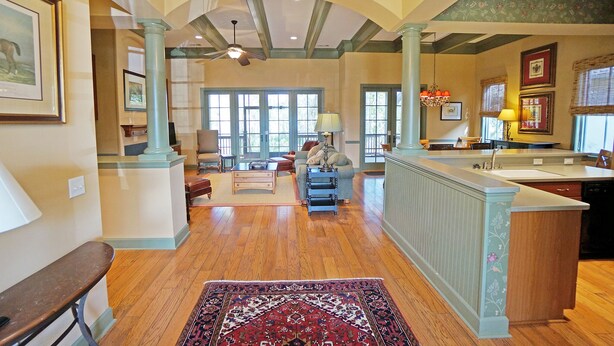 A spacious living room with hardwood floors, a large rug, and a sofa. - Hampton Hall Golf Cottage (Bluffton)
