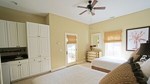 A bedroom with two beds, a ceiling fan, a window with a view, and a bathroom with a shower and toilet. - Hampton Hall Golf Cottage (Bluffton)
