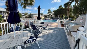 Ein Pooldeck mit Liegestühlen, Sonnenschirmen und Grillmöglichkeiten.