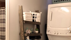 Ein kleines Badezimmer mit Toilette, Waschmaschine und einem Holzkosmetikschrank mit Spiegel.