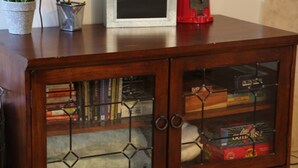 Un meuble en bois doté de portes en verre, renfermant des livres et des jeux de société.