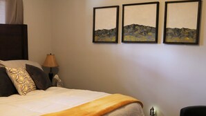 Ein Schlafzimmer mit einem Bett, einem Deckenventilator, einem Nachttisch, einer Lampe und drei gerahmten Bildern an der Wand.