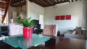 A modern living room with a glass coffee table, a red potted plant, a wooden ceiling, and a red wall decoration. - Appartement Authentique Dans le Centre de Caen (Caen)
