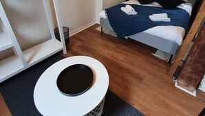 A bedroom with a bed, a desk, a chair, a hanging clothes rack, and a small trash bin. - Appartement Authentique Dans le Centre de Caen (Caen)