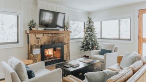 A cozy living room with a fireplace, a Christmas tree, and comfortable seating.