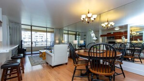 A modern hotel room with a dining area, a sofa, and a TV. - Monthly Discovery Bay 1713 Ocean/City Views 1 Bd 1Ba (Honolulu)