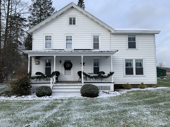 A two-story white house with a front porch, a front door, and a visible number '571'.