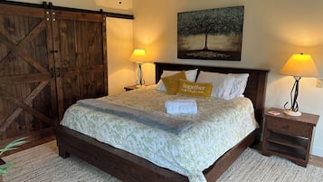 A bedroom with a wooden bed, two bedside lamps, a painting on the wall, and a ceiling fan.