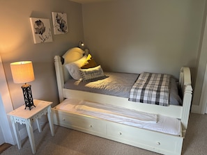 A single-bed room with a white headboard, a bedside table with a lamp, and a small drawer. - The Farmhouse - 2 ml from Colgate, king bed, family friendly, sleeps 10 (Hamilton)