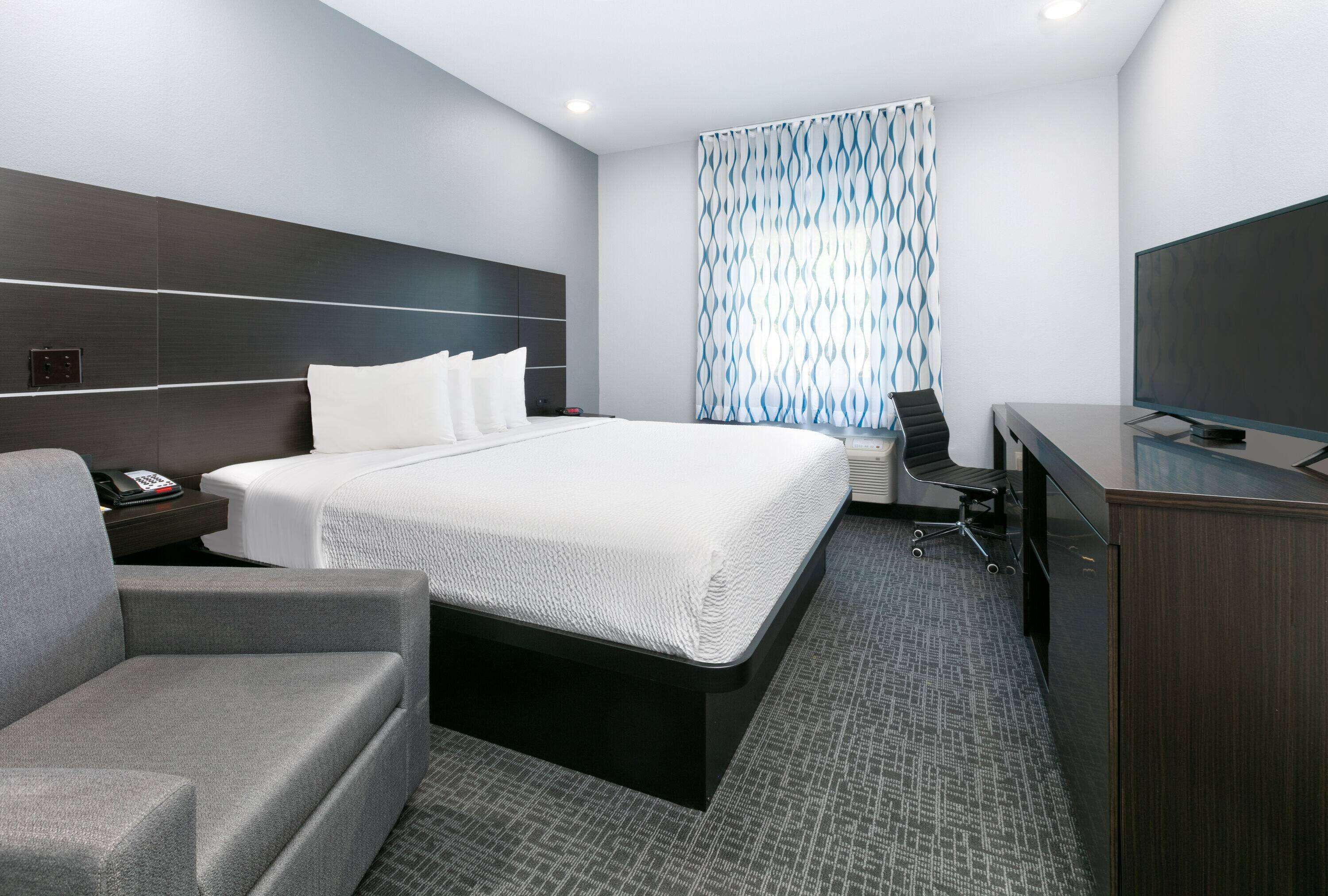 Una habitación de hotel moderna con una cama grande, un escritorio, una silla y un televisor.